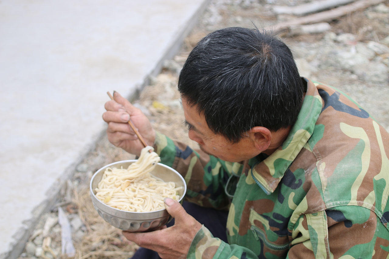 图为一名民工在吃中餐,只是一碗简单的面条,而民工们的工作其实是非常