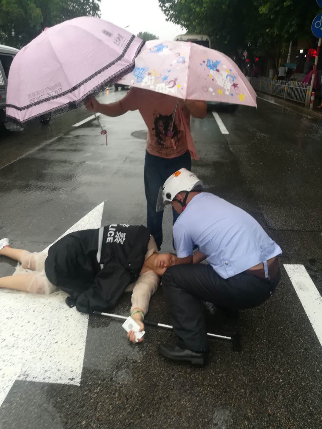 女子受伤躺路上 交警冒雨施救