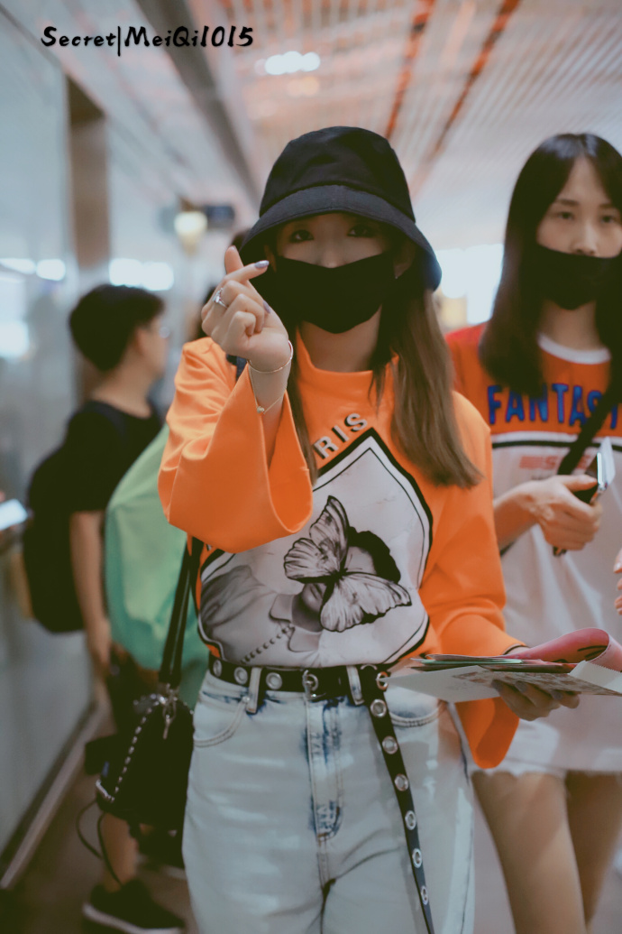 孟美岐戴渔夫帽和口罩穿橙色卫衣现身机场,用手比心卖萌好可爱!