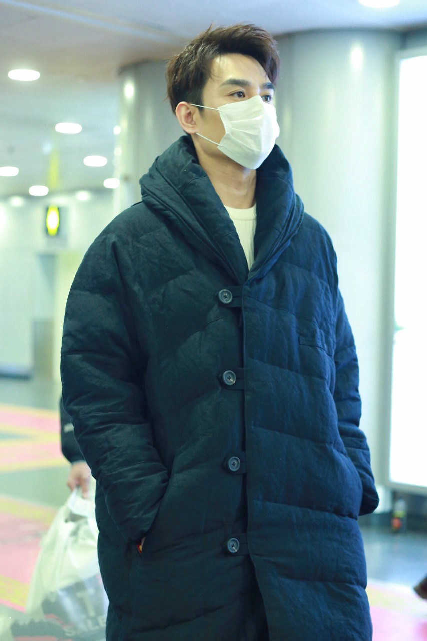 王凯戴白色口罩穿黑色长款羽绒服现身机场,穿着非常保暖了