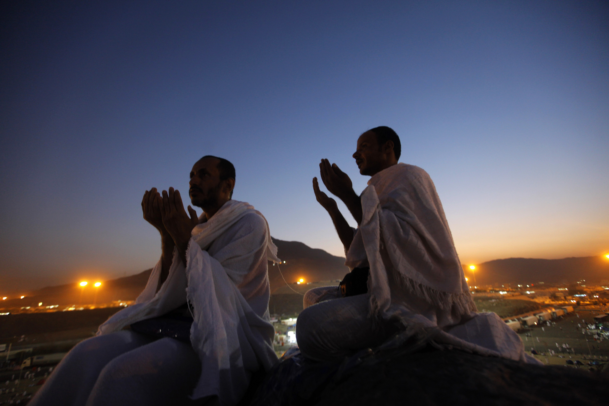 沙特阿拉伯圣城麦加附近,两位穆斯林朝圣者在阿拉法特山上虔诚祈祷