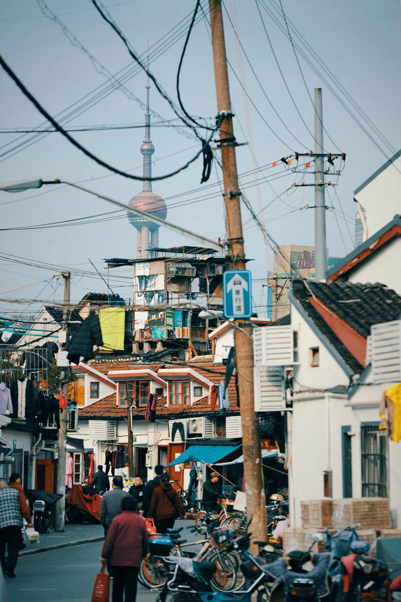 上海老弄堂拍摄,近处低矮杂乱的老房子与远处外滩的现代化建筑形成