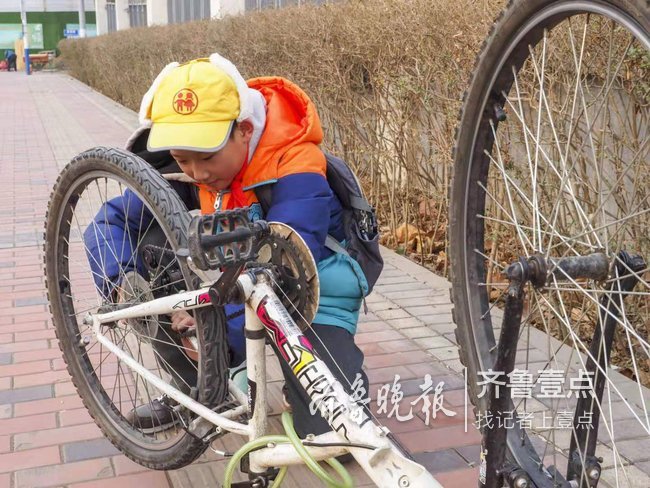 一小学生在路边信心满满的修理自己的变速自行车,不禁为孩子的自理