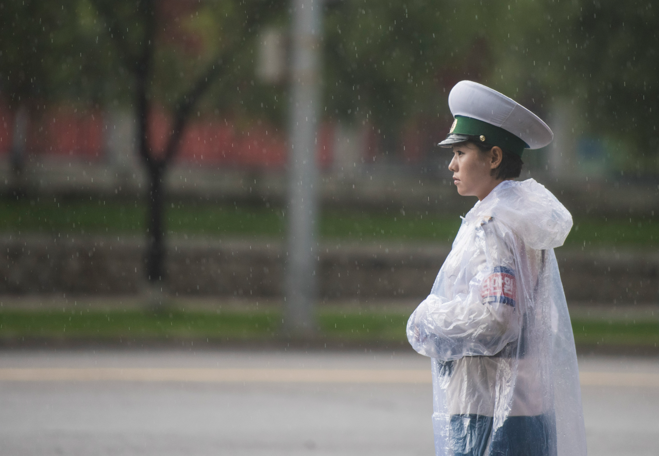图为朝鲜平壤,一名穿着工作制服的女交警,正在下雨天认真的执勤.