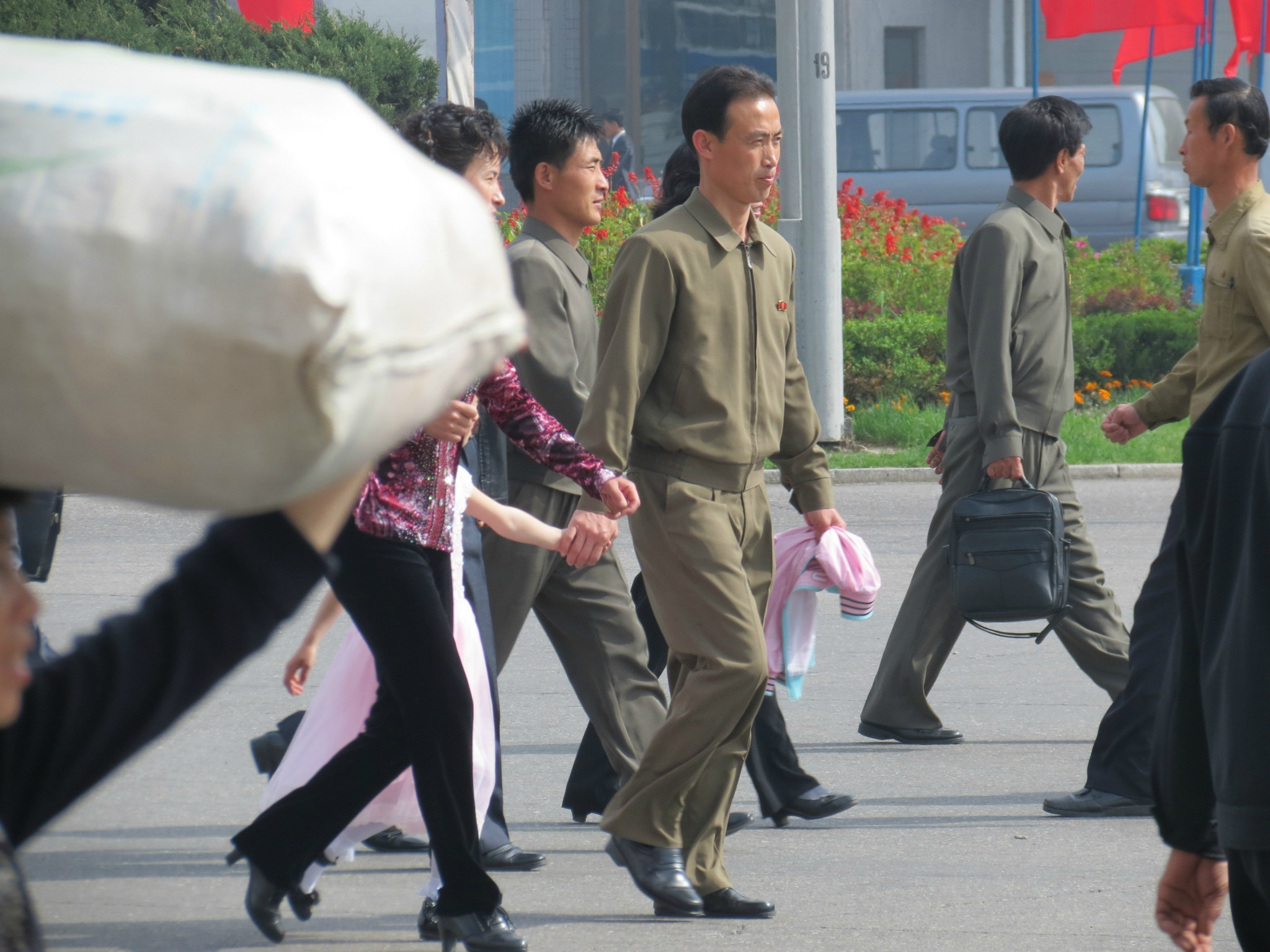 图为朝鲜平壤街景,人们匆匆步行着,有人扛着一蛇皮袋货物.