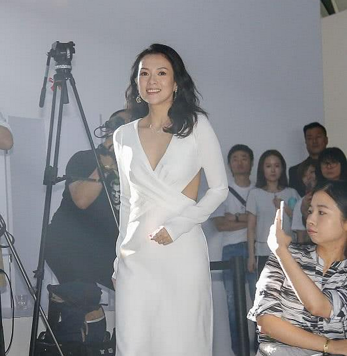 章子怡左手,稍微握住裙子,似乎有点长,左手的两个戒指也很是显眼.