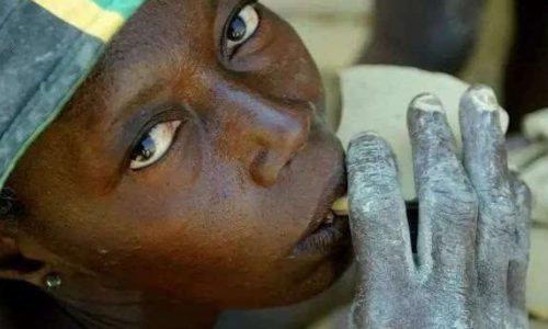 图为非洲的一位小孩正在食用泥饼,小孩们很喜欢吃,认为味道很好.