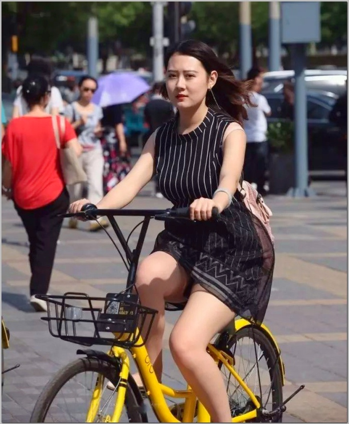 这位骑黄色自行车的美女才是亮点,看她的裙子好漂亮呀,黑白竖条的
