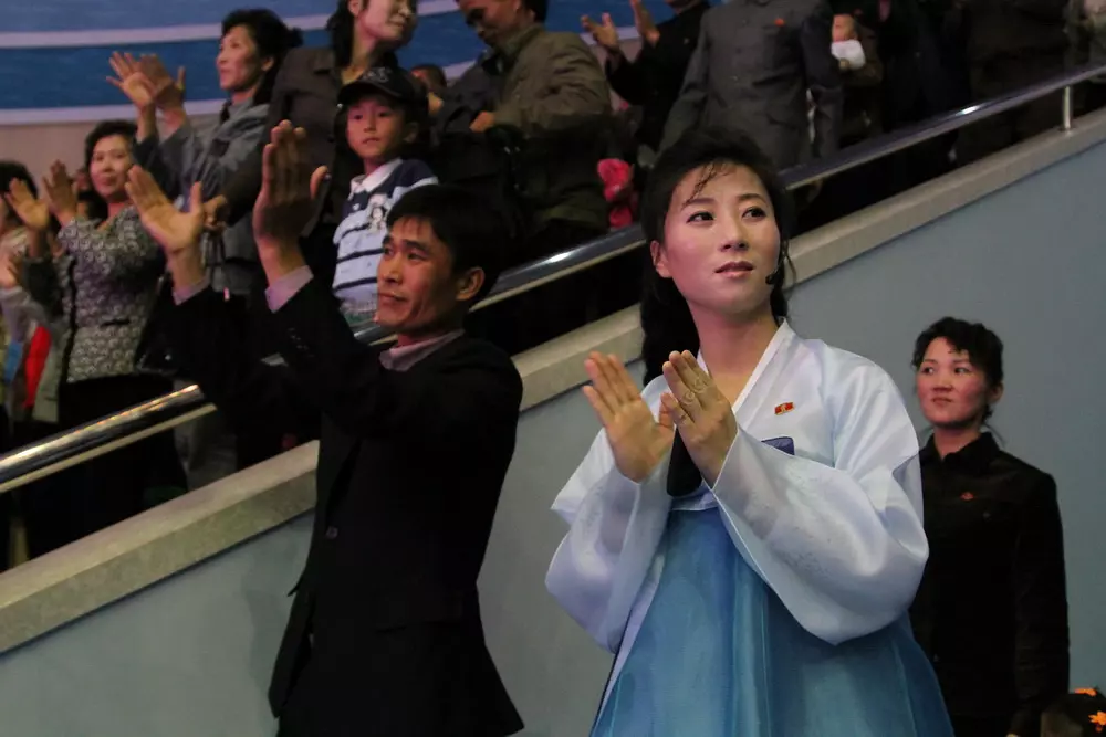 图为一名观看演出的朝鲜女子,正在微笑着鼓掌.