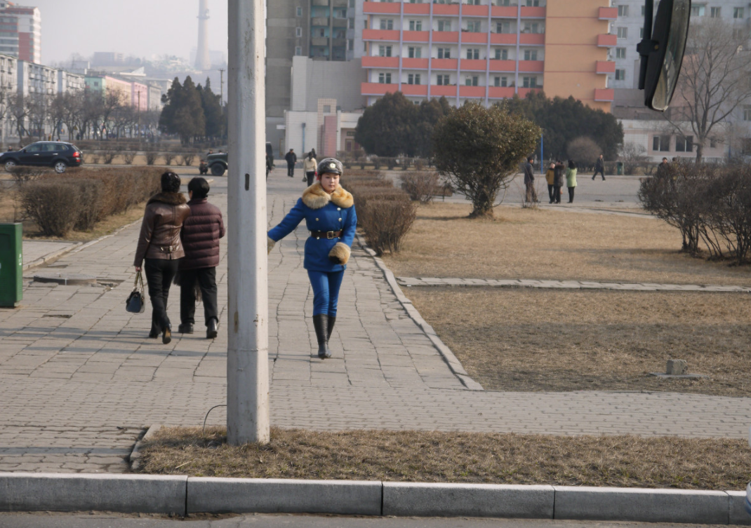图为朝鲜平壤冬日街头,一名穿着制服的女交警大步走在路上.