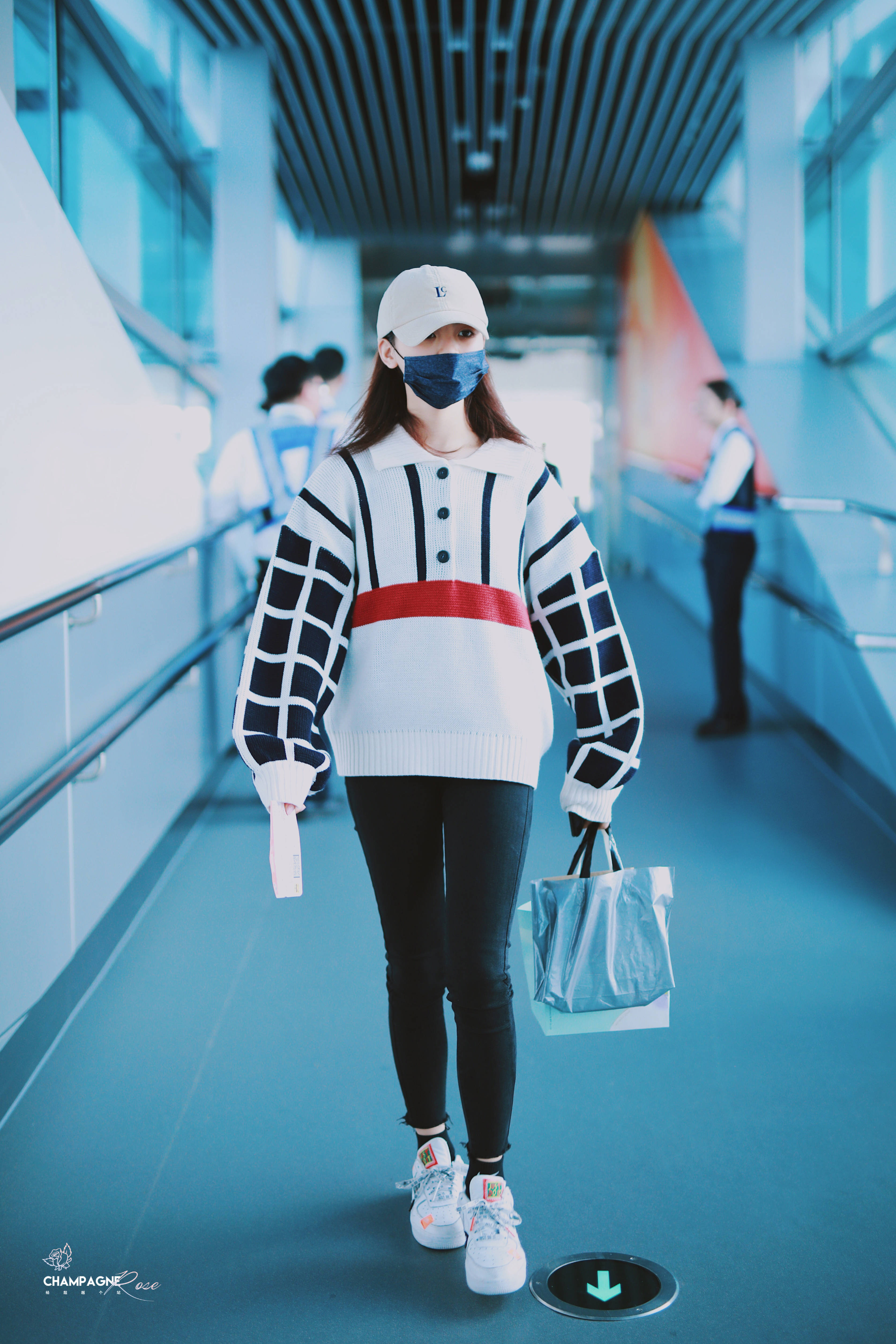 杨超越穿红黑白拼色毛衣现身机场,戴白色棒球帽和黑色口罩遮面