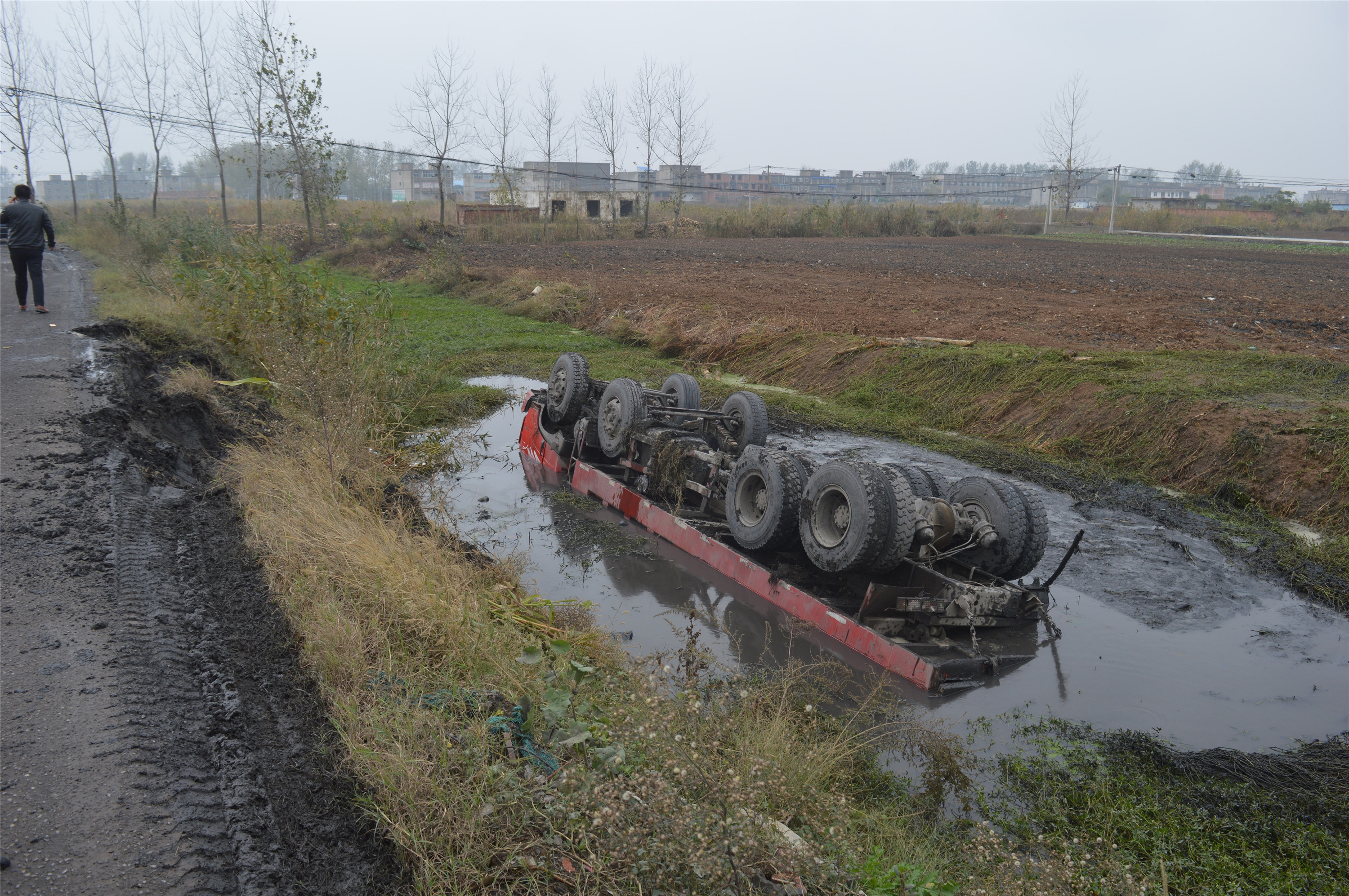 货车侧翻水沟底朝天,司机安全逃脱成泥人
