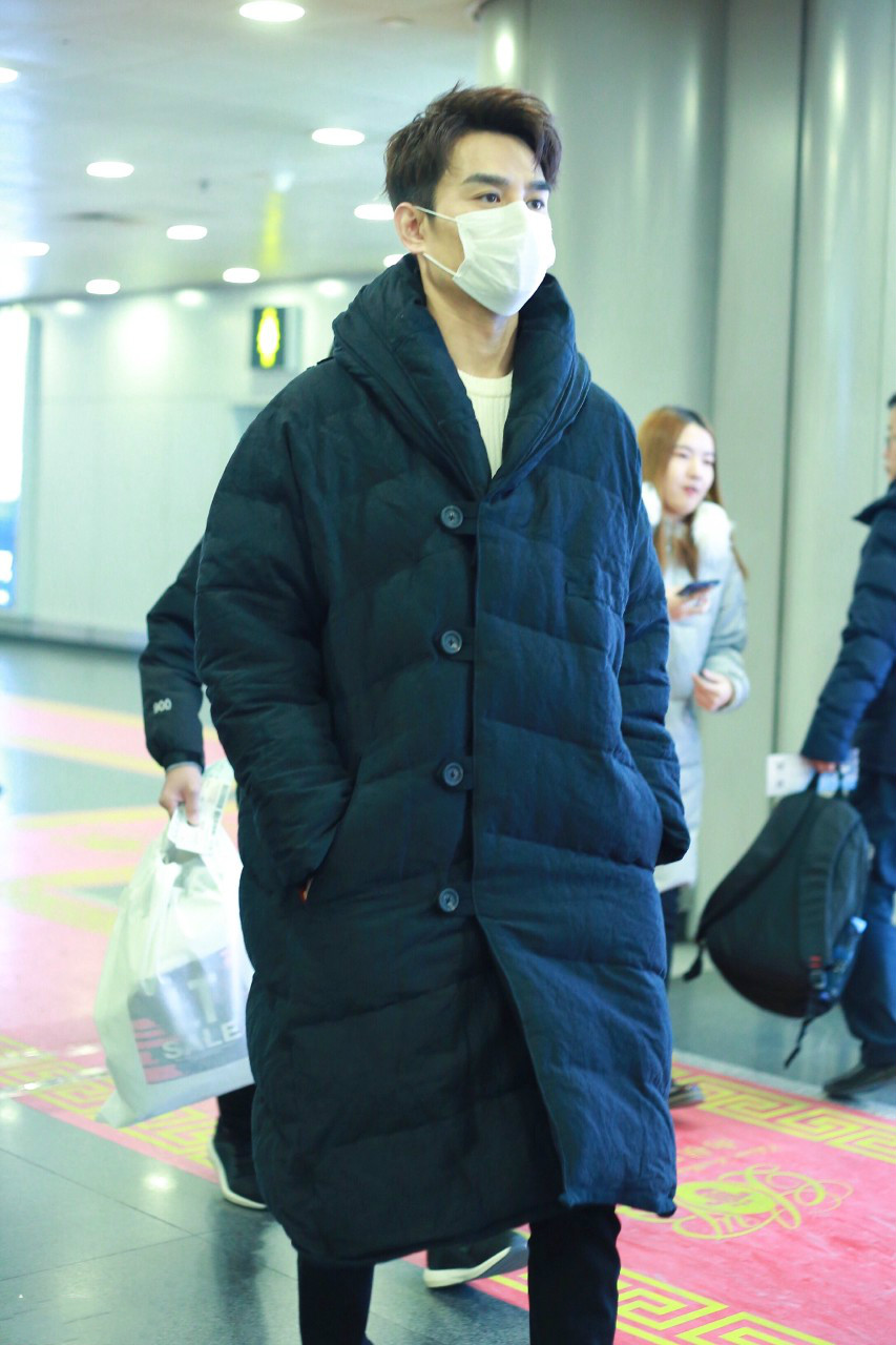 王凯戴白色口罩穿黑色长款羽绒服现身机场,穿着非常保暖了