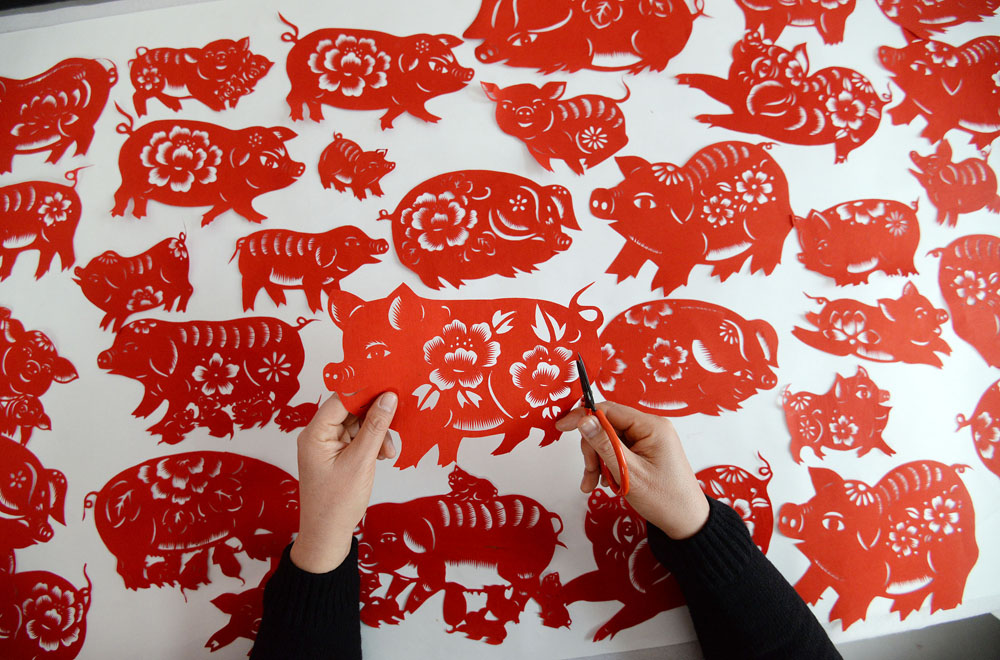 河北省邯郸市复兴区民间剪纸艺人冯石萍在创作猪年剪纸作品.