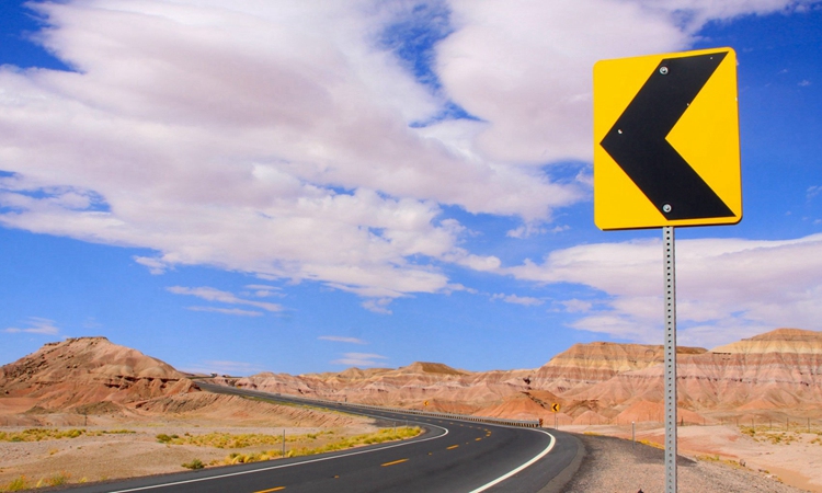 公路蜿蜒到远方,道路两侧是小山石,蓝蓝的天空里有大片大片的云朵.