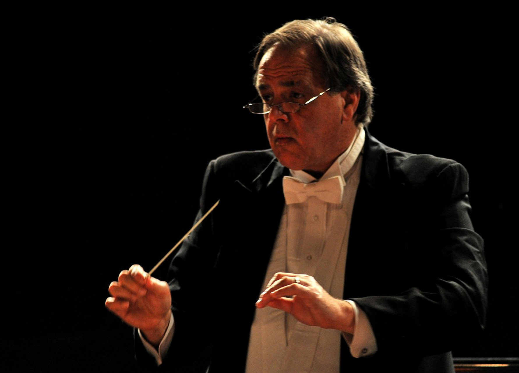 交响乐指挥家在指挥交响乐团时,负责解读乐谱,动作示范,引导乐团成员