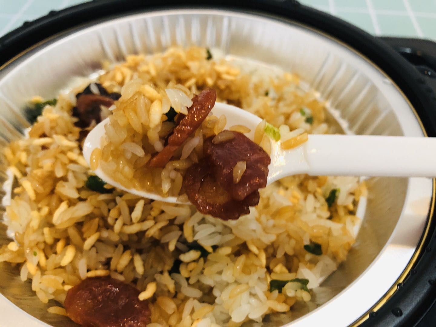 揭开盖子米饭已经熟了,倒入秘制煲仔汁拌一拌,再撒上炒米,一碗煲仔饭