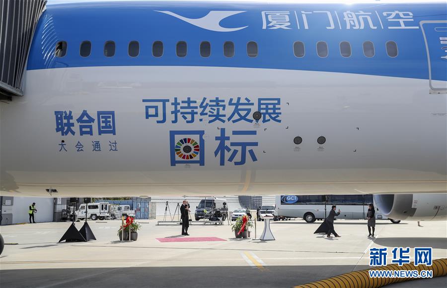 空乘人员展示厦航首架涂装宣传联合国可持续发展目标的客机