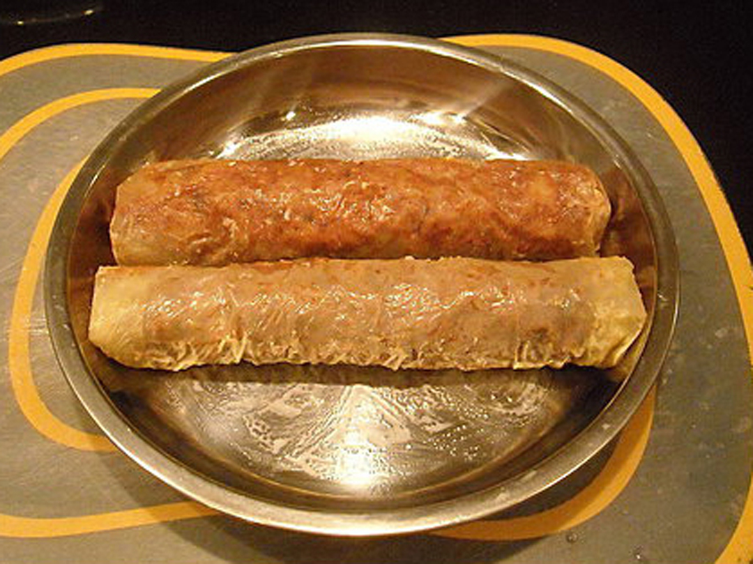 6. 裁剪两张长方形干腐皮,将一半的红麴面肠,平均摊在腐皮上.