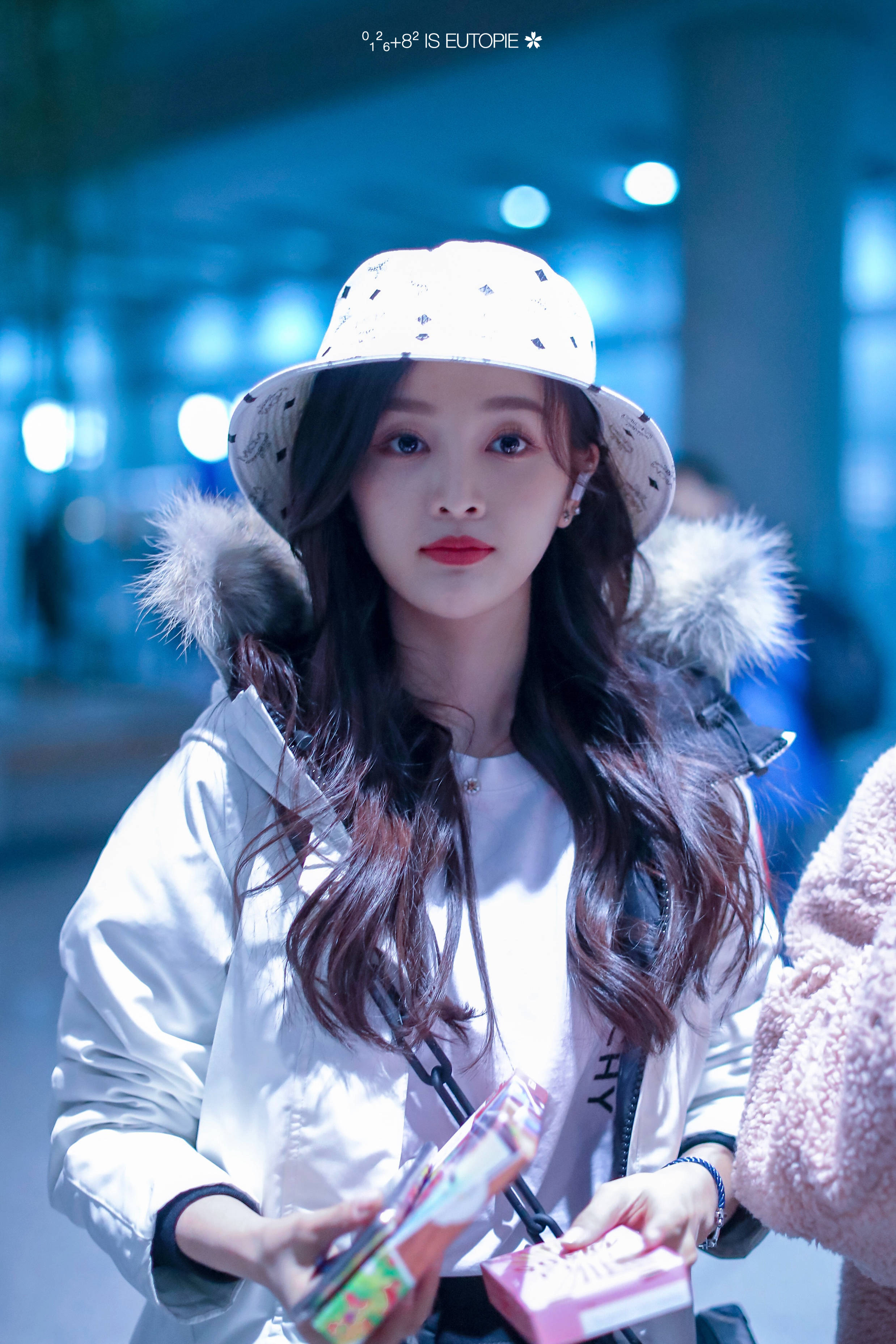 吴宣仪戴白渔夫帽穿白外套搭配黑裤子现身机场,皮肤白皙面带微笑