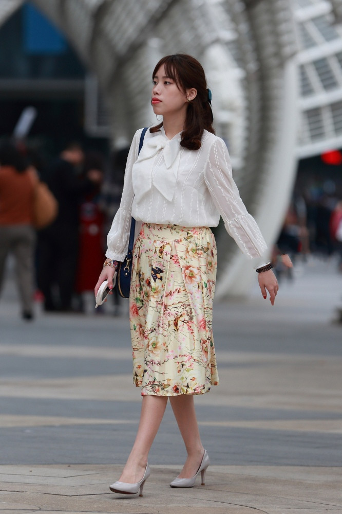美女身穿白色上衣搭配半身裙,清新亮丽