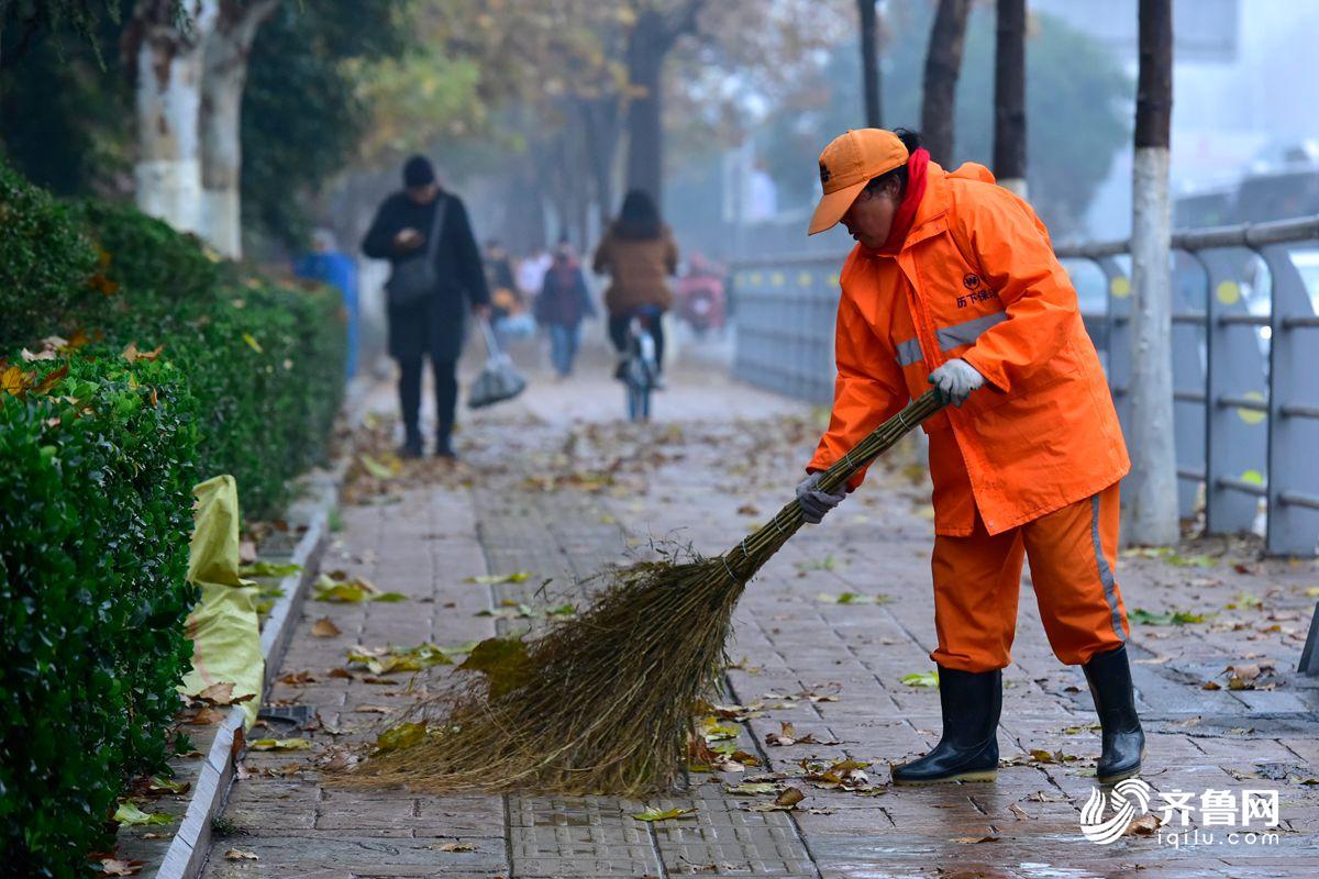 清晨的濟南街道上,環衛工忙碌地清掃著這一夜落下的樹葉.