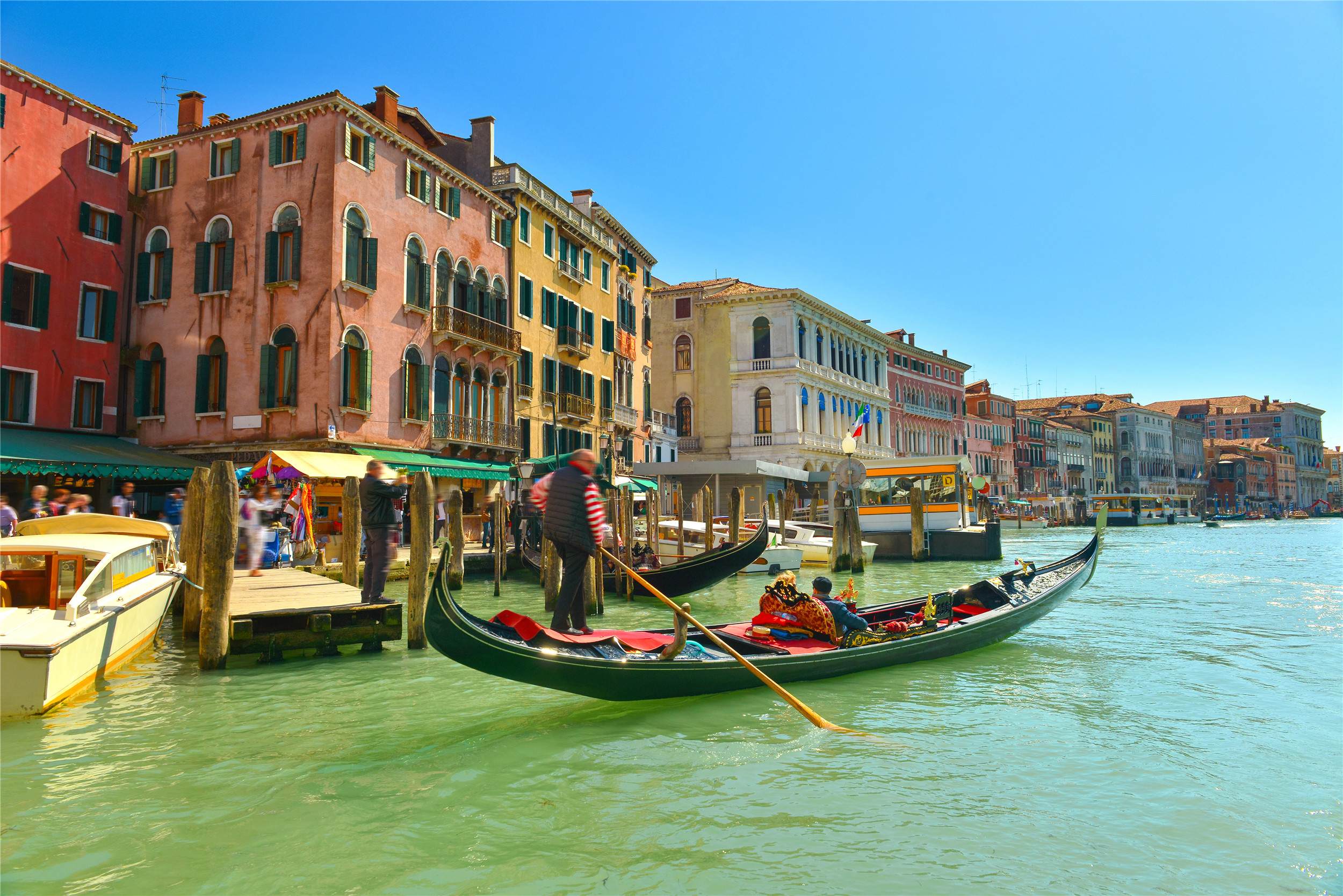 一人撑着一片小船行驶在河面,船的造型有风格,很帅气.