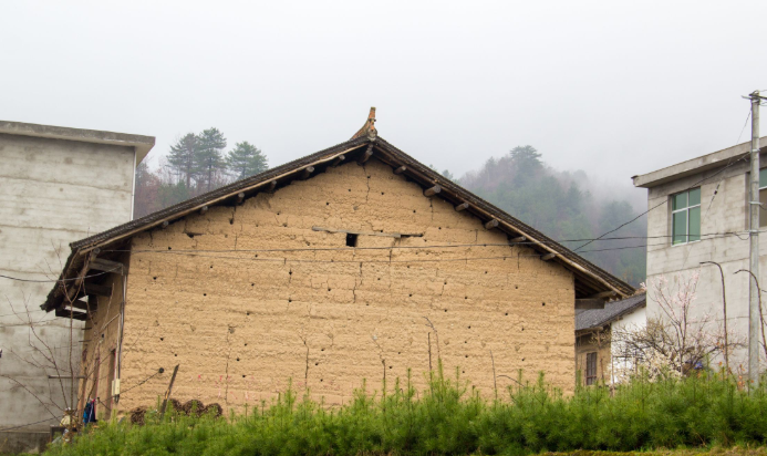 这栋土墙老房子,是上个世纪五六十年代的记忆,如今被紧紧地夹在两栋新