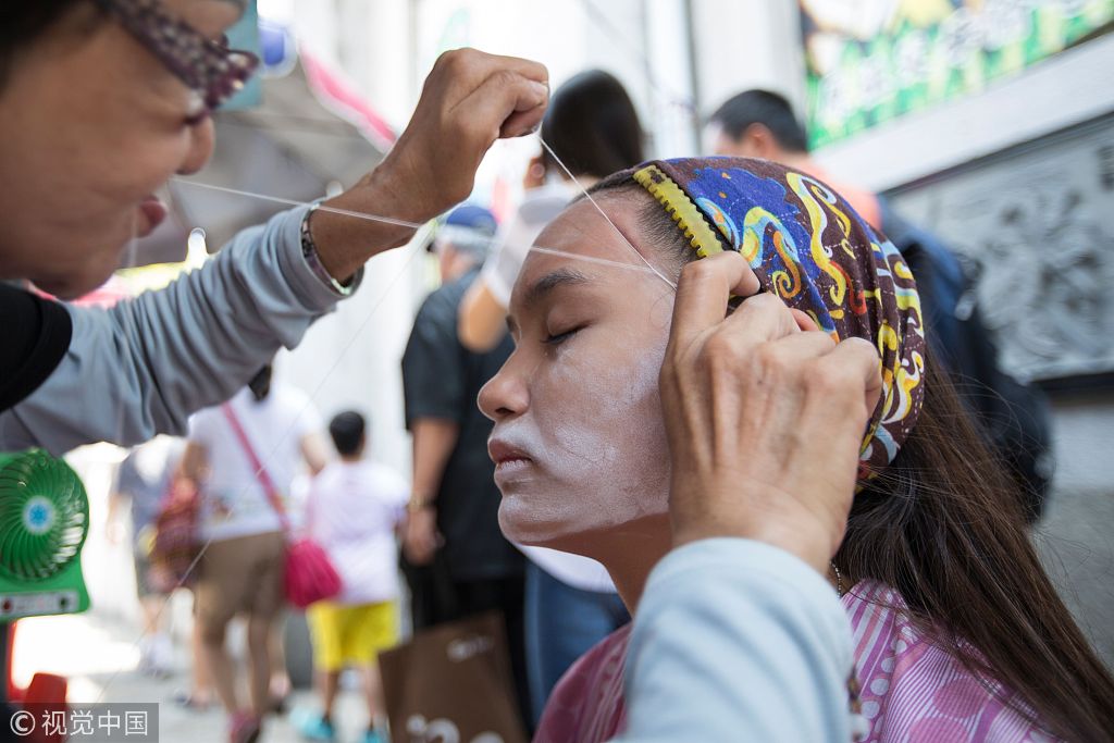 街头"绞脸"受欢迎 男子也来体验一把古代美容术