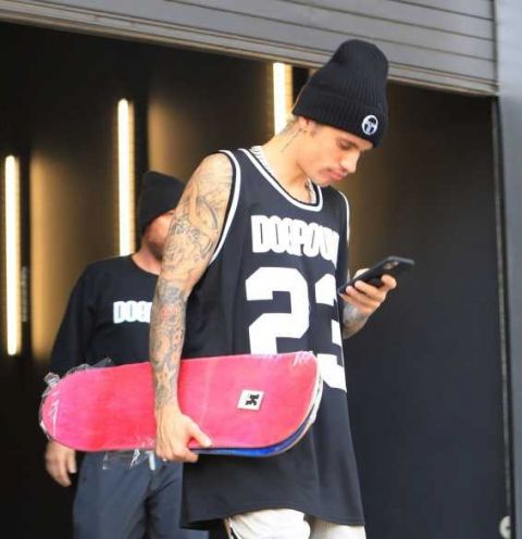 比伯着运动装手持滑板现身街头 大露花臂纹身秀肌肉