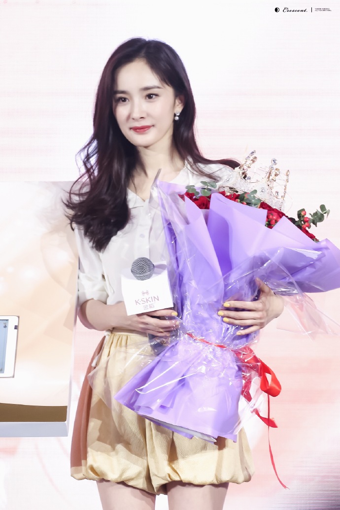 杨幂穿白衬衣搭配黄短裤亮相代言活动,手捧鲜花皮肤白皙面带微笑