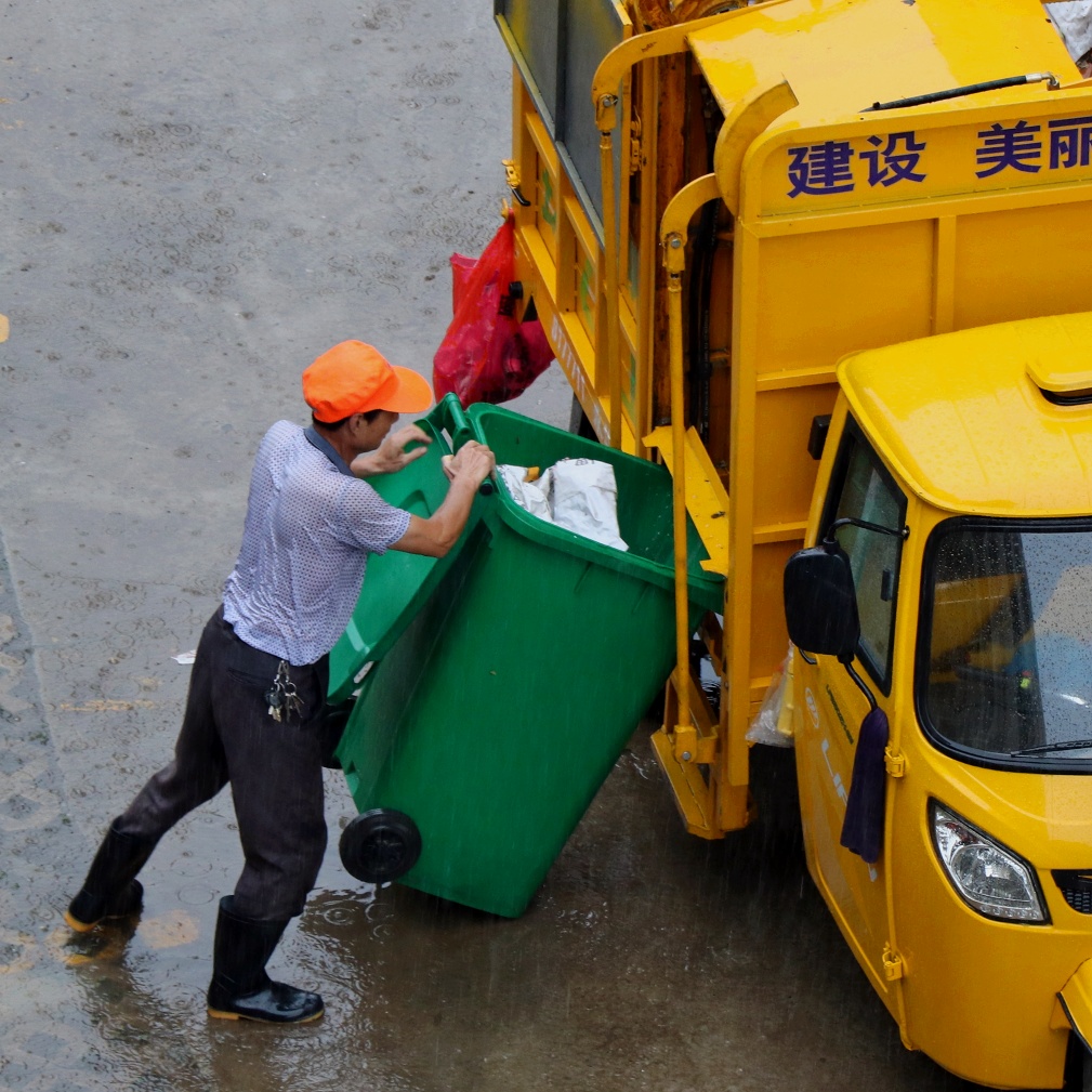大雨中收集小区垃圾的清洁工