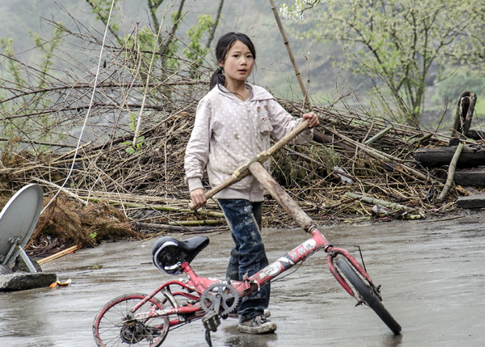 乡村儿童也有一双巧手,破车上装上木棍做的龙头,妹妹骑着很快乐