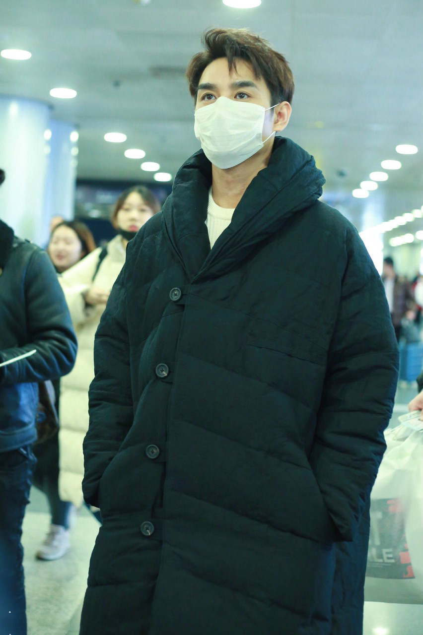 王凯戴白色口罩穿黑色长款羽绒服现身机场,穿着非常保暖了