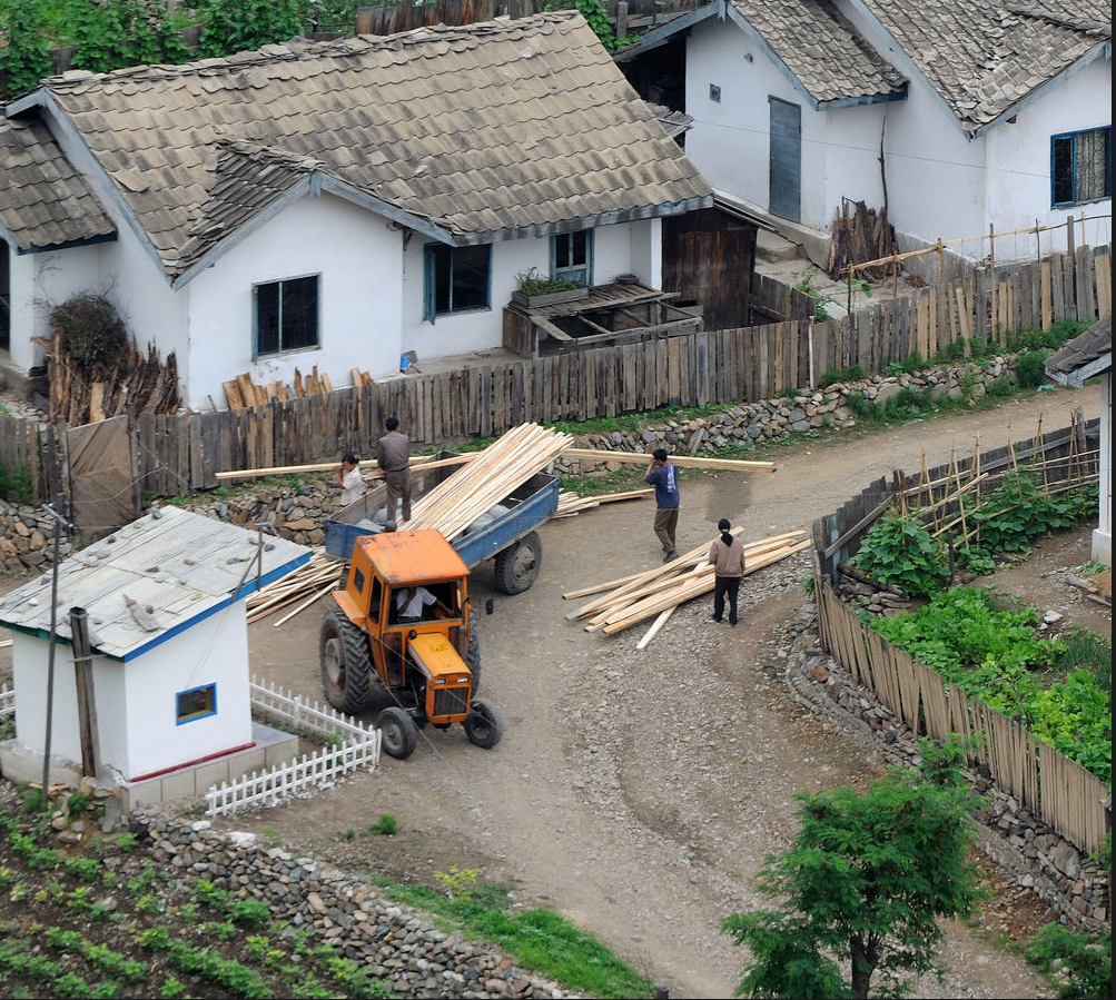 图为朝鲜农村地区,一群朝鲜男人正在搬运木材