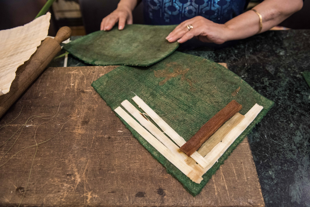 在埃及吉萨省,一名莎草画店员工展示莎草纸的制作过程.