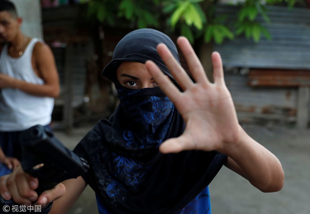 洪都拉斯圣佩德罗苏拉,barrio-18帮派的一名年轻成员举枪打手势