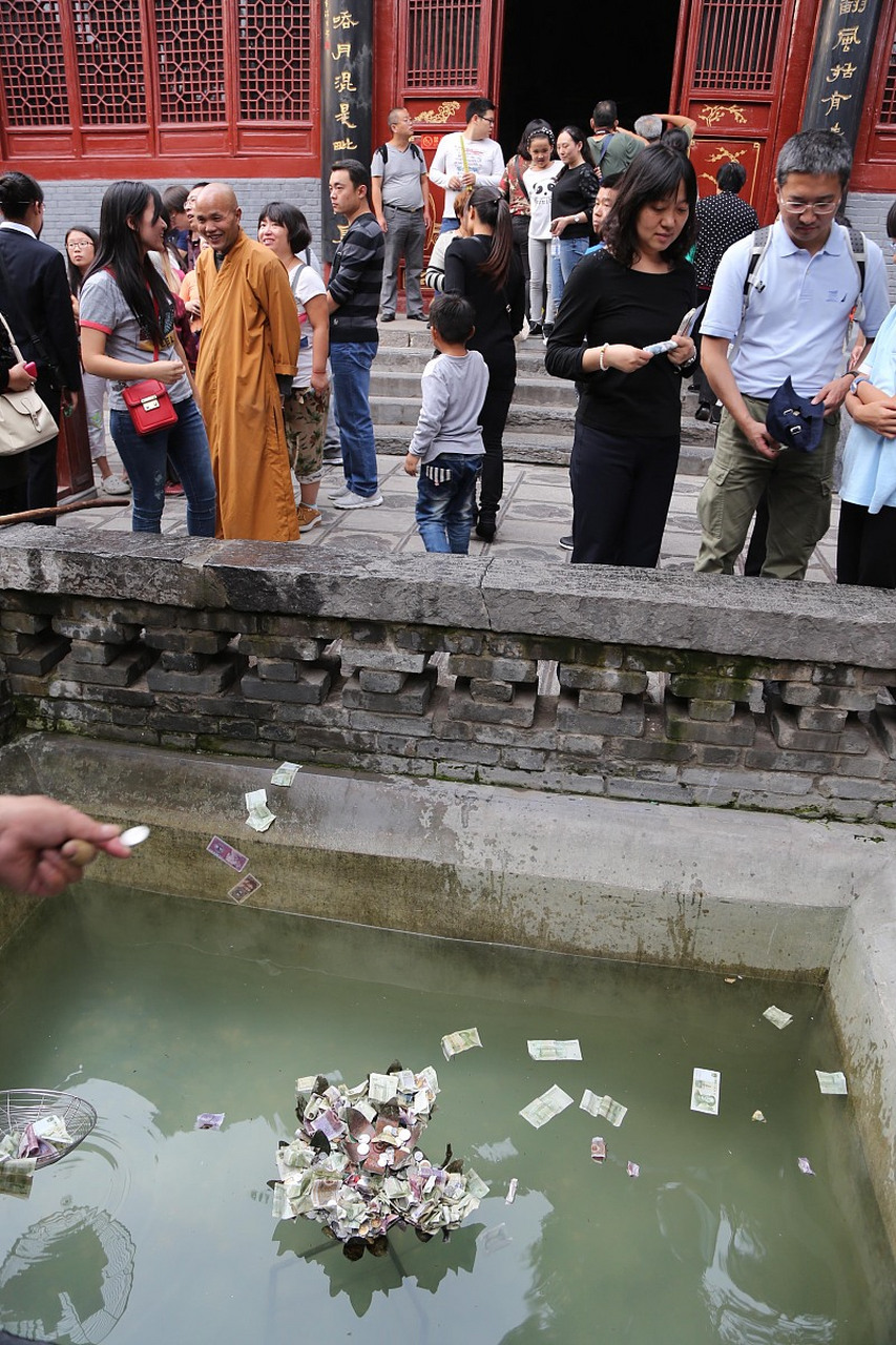 视频中,一位女子带着孩子在景区捞许愿池里的硬币,这一行为引起了公众