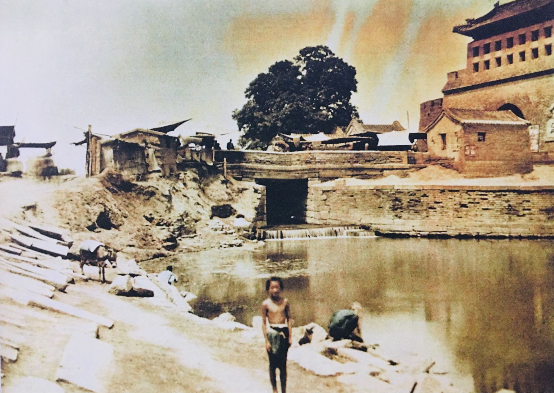 拍摄于1910年代,一个孩子在护城河边,不远处就是永定门城楼.