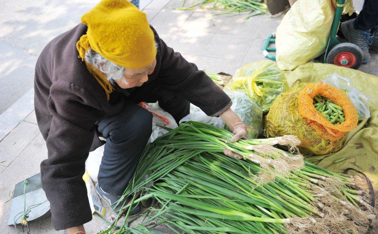 繁華喧鬧的大城市路邊,一位農村老奶奶賣蔥,一男子扒來扒去