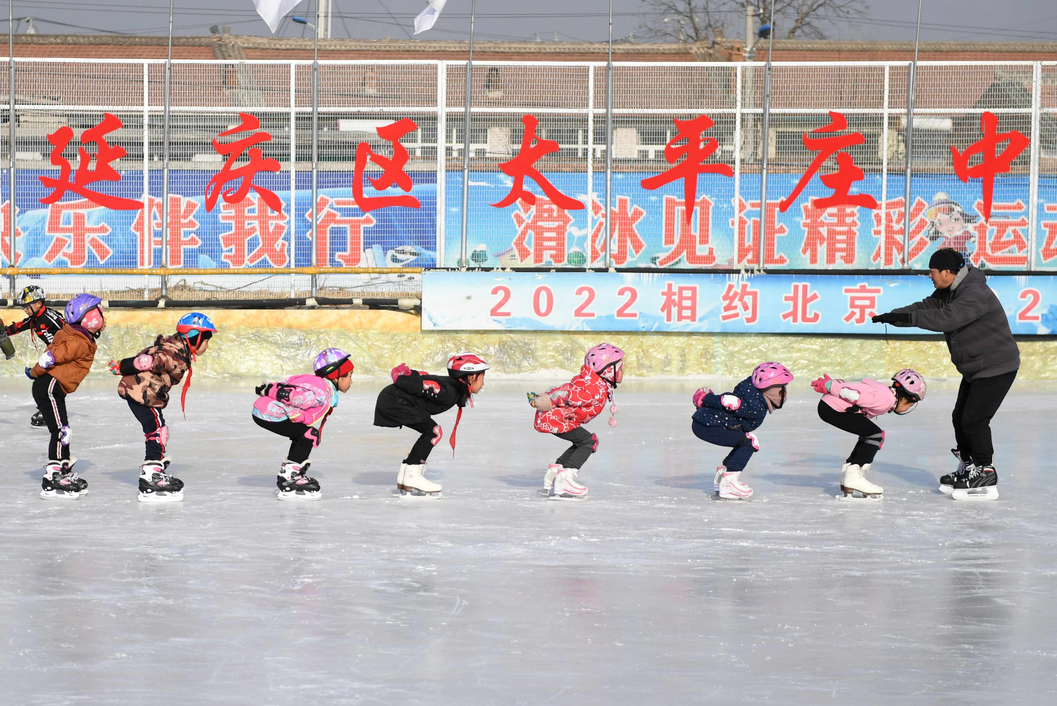 北京延慶太平莊中心小學學生在教練李淳宇(右一)指導下練習滑冰動作