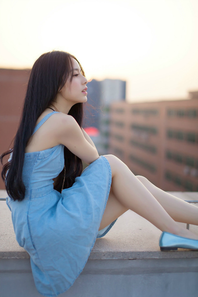 一个依偎在楼顶阳台上的清秀美女姑娘
