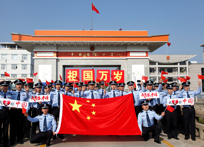 图们边检民警国门前高举国旗 喜迎新中国成立70周年