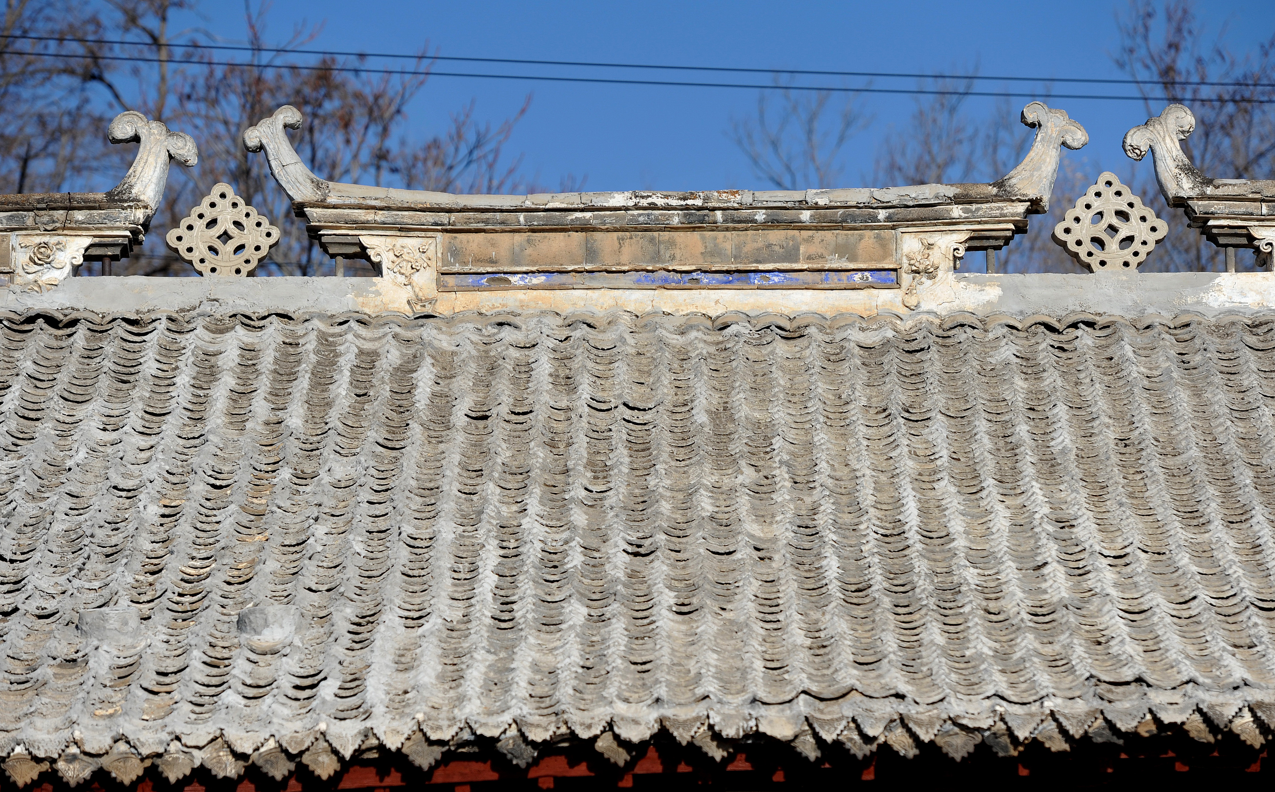青瓷瓦房的屋顶呈人字形,房盖有鱼鳞青瓦,飞檐中间,两对螭吻相对,中间