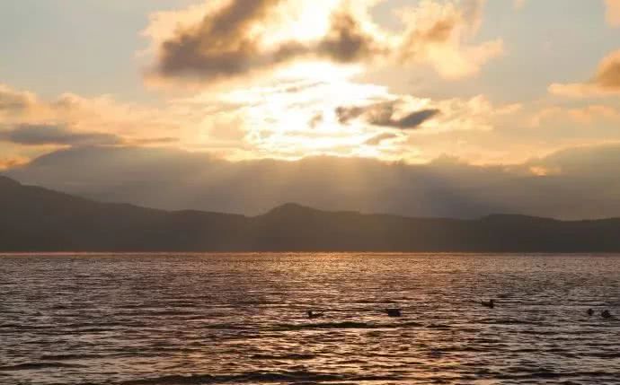 在日出时,湖面波澜壮阔,猪槽船惊扰了美梦,在氤氲的水汽中缓缓前行.