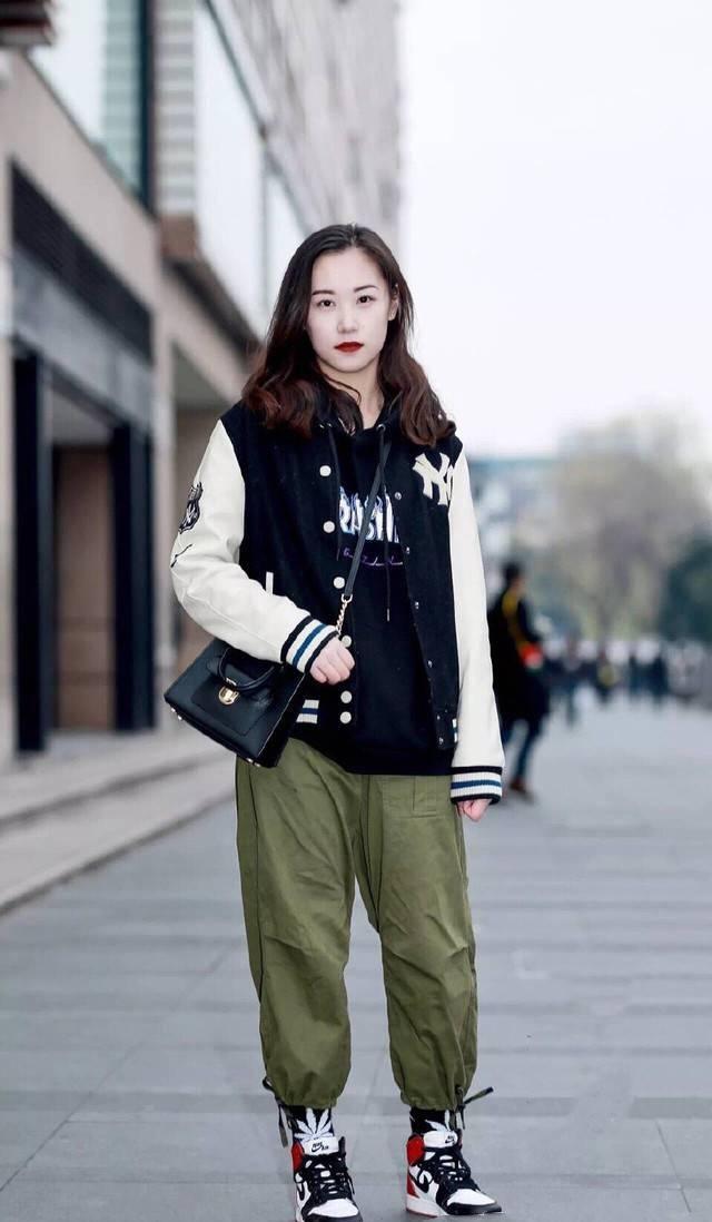 帅气十足的女生,身穿黑色外套搭配绿色裤子,非常有个性