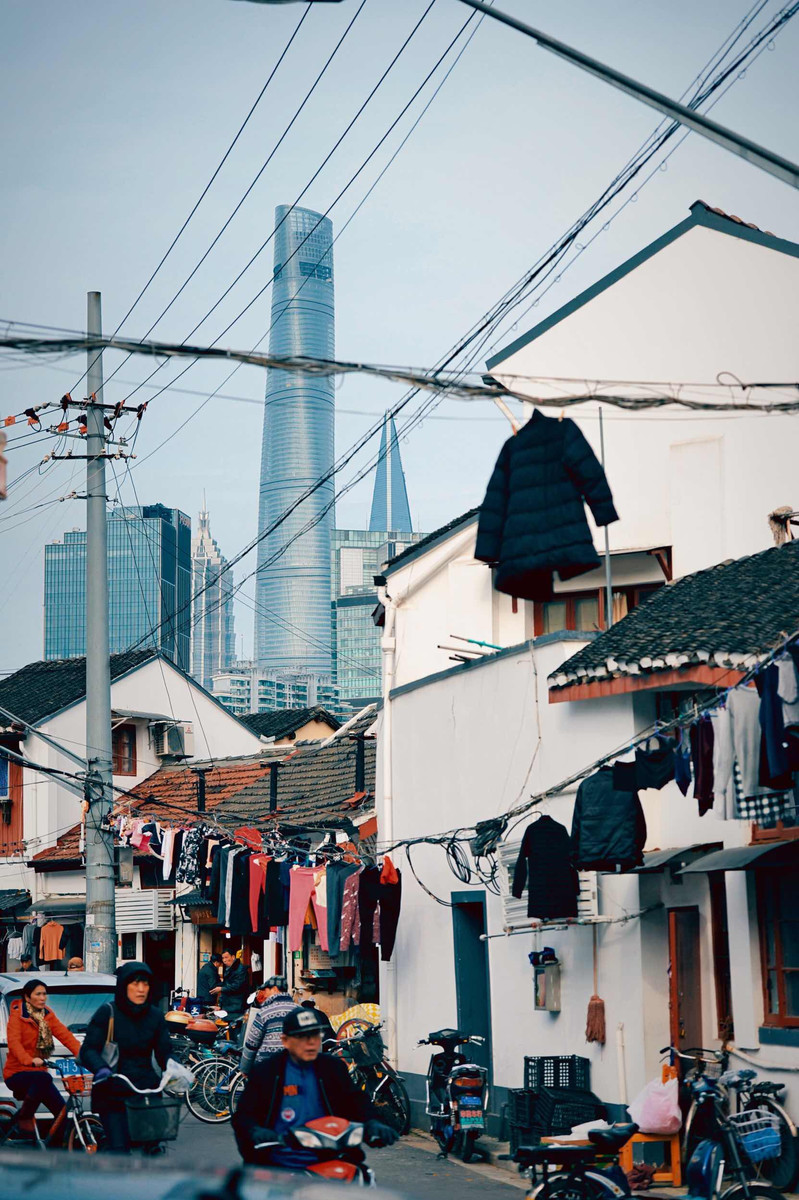 上海老弄堂拍摄,近处低矮杂乱的老房子与远处外滩的现代化建筑形成