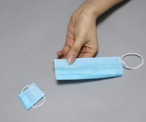 首先准备一个一次性口罩,将它的一端给剪开.