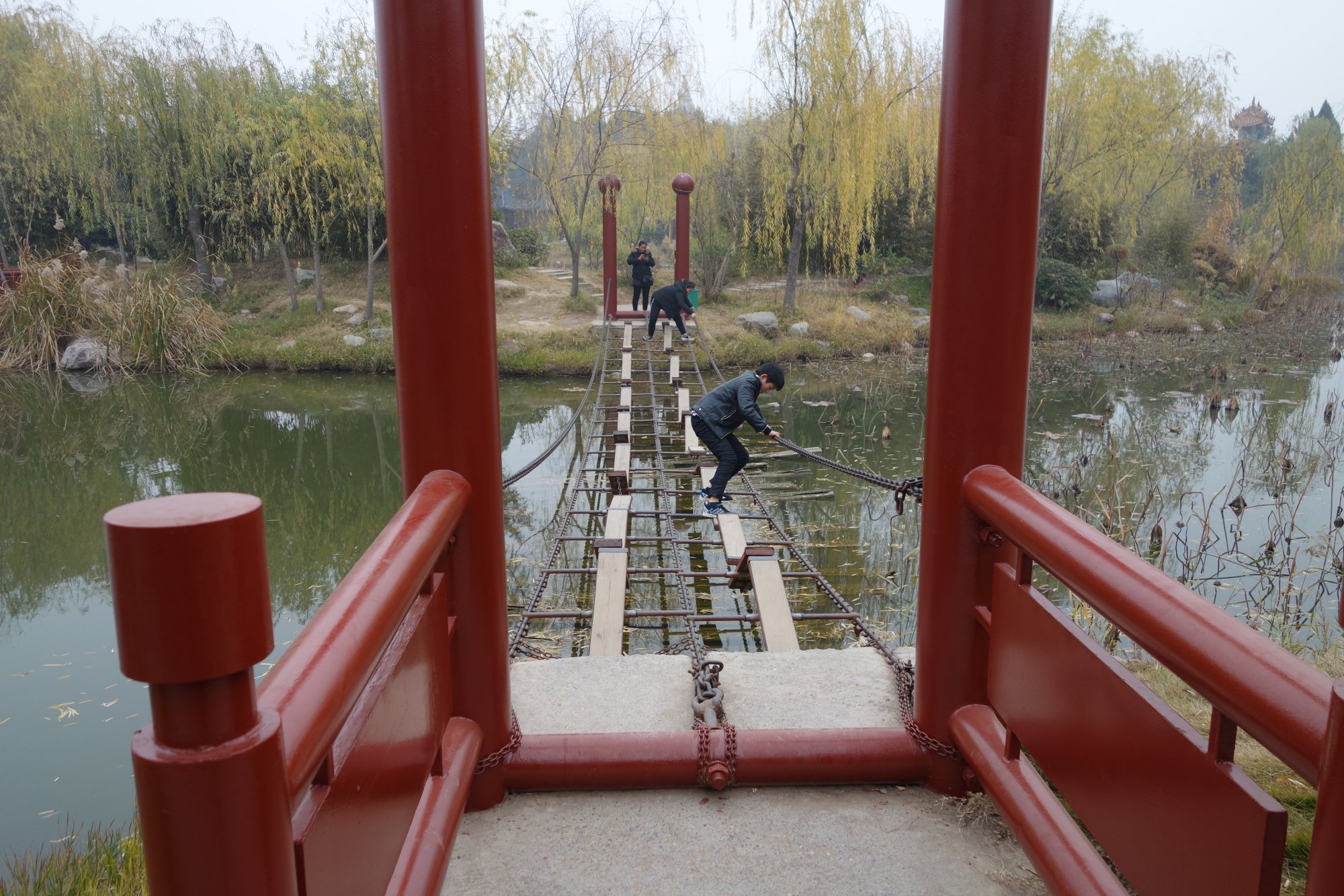 铁链桥,上面的木板和跷跷板一样,通过时要护裆,除非踩着铁链通过.