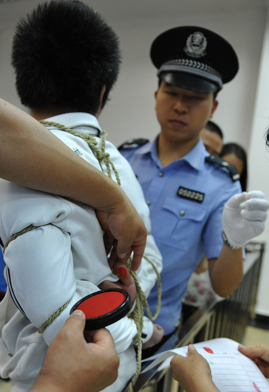 画面中的他正在听从法警的安排,用捆绑的拇指,在死刑执行书上按下手印